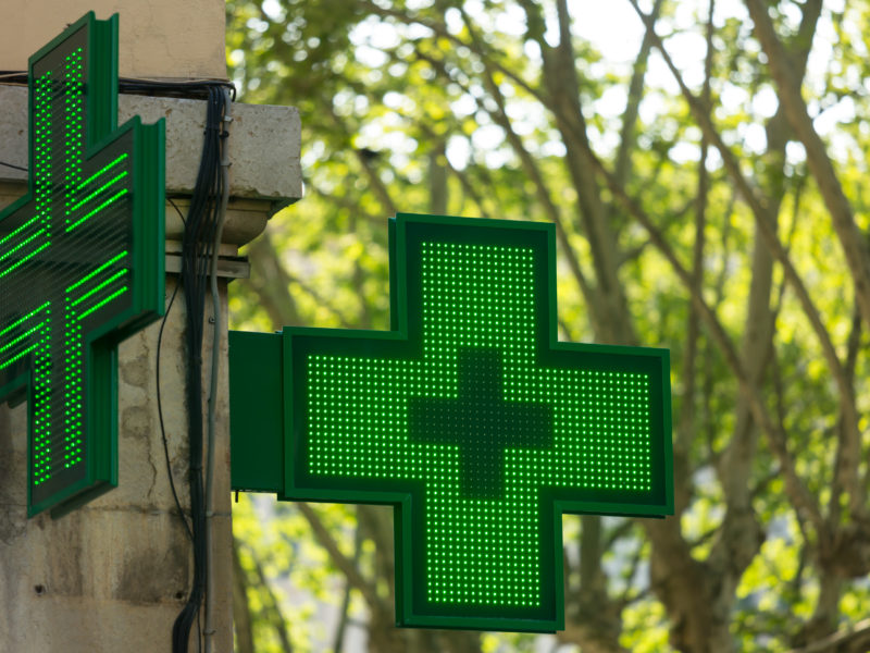 Closeup of a green pharmacy sign outside a pharmacy store in France.