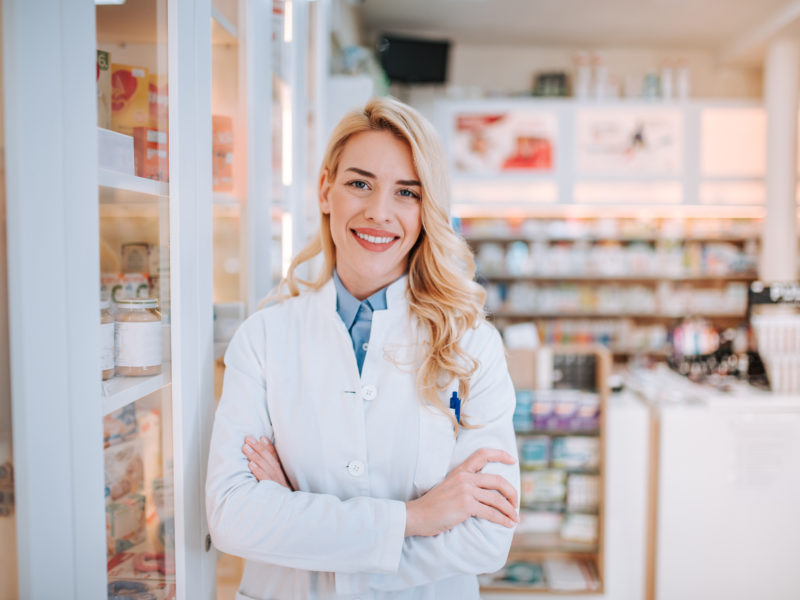 Cheerful pharmacist chemist woman standing in pharmacy drugstore